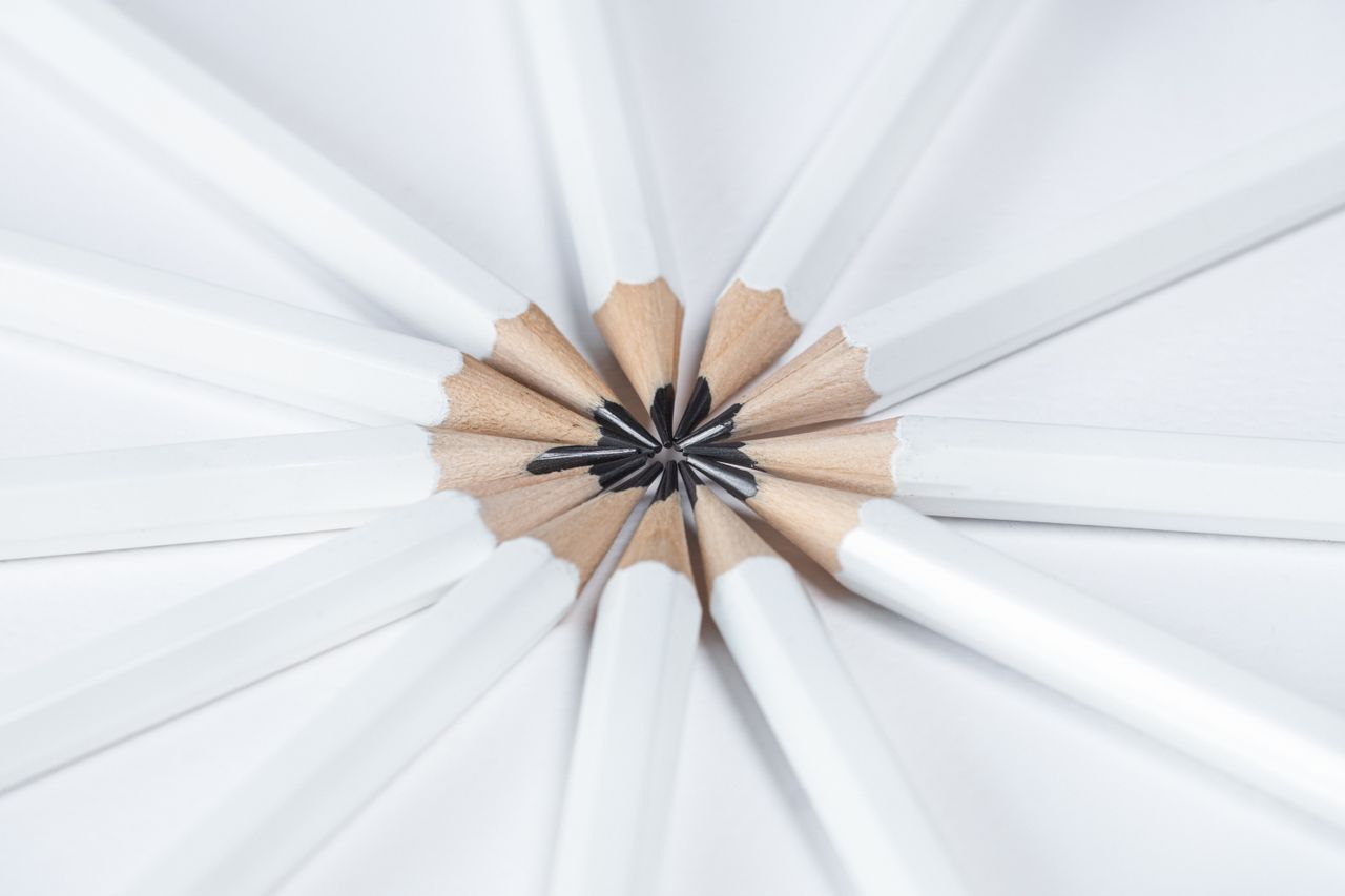 Top view of white pencils arranged in a radial pattern on a white background, emphasizing harmony and creativity.